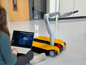 person sitting with laptop next to robot